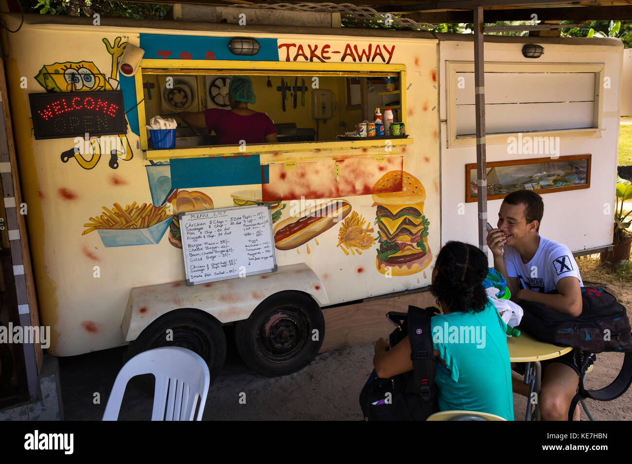 The Seychelles, Mahe, Port Launay, customers at small local takeaway food, stall Stock Photo