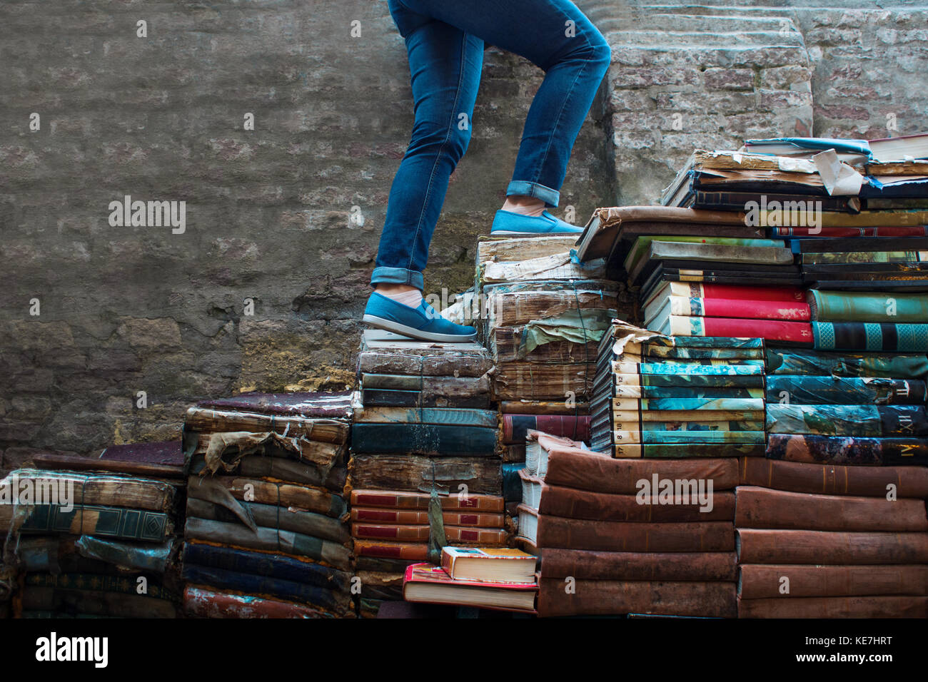 Education, concept. A young woman climbs up the stairs of books Stock Photo