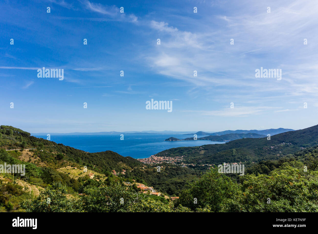 Horizontal view down on small town Marciana Marina on the coast of Elba island in Mediterranean sea. The hills and mountains around are covered by tre Stock Photo