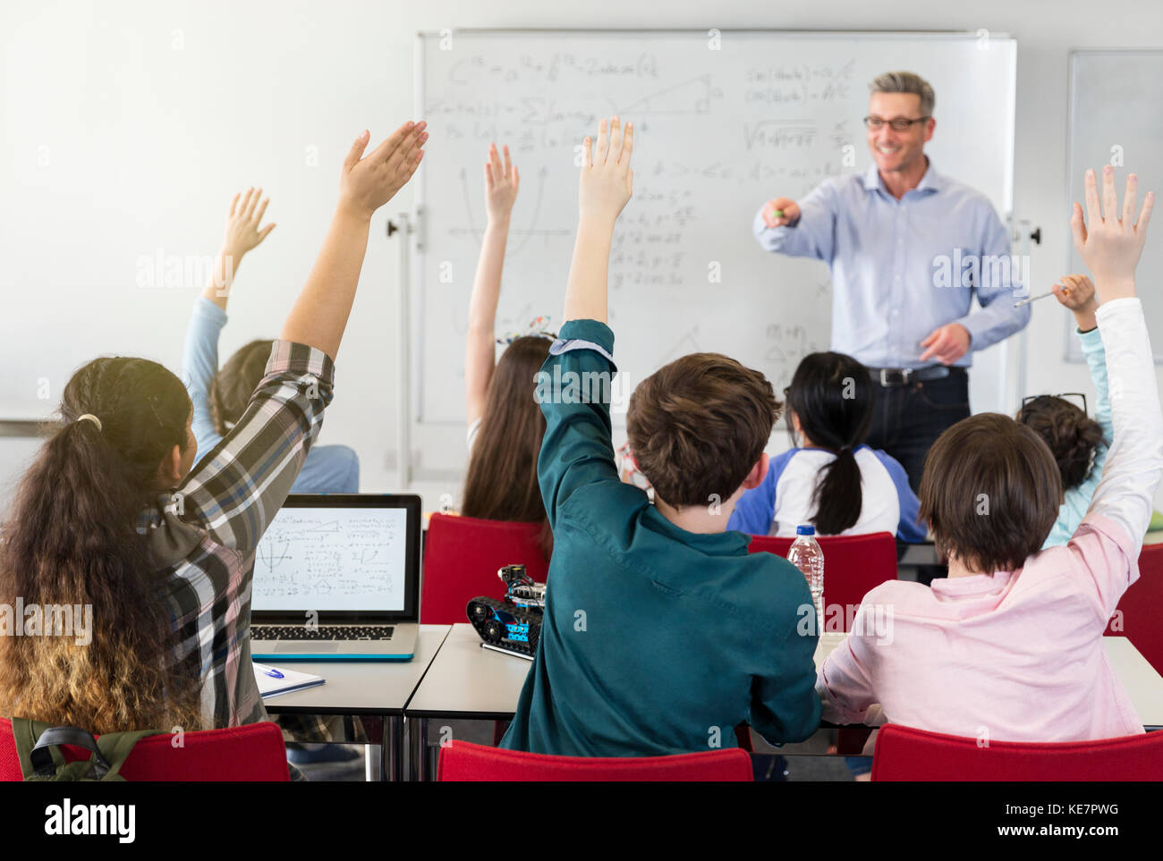 Male teacher calling on students in classroom Stock Photo
