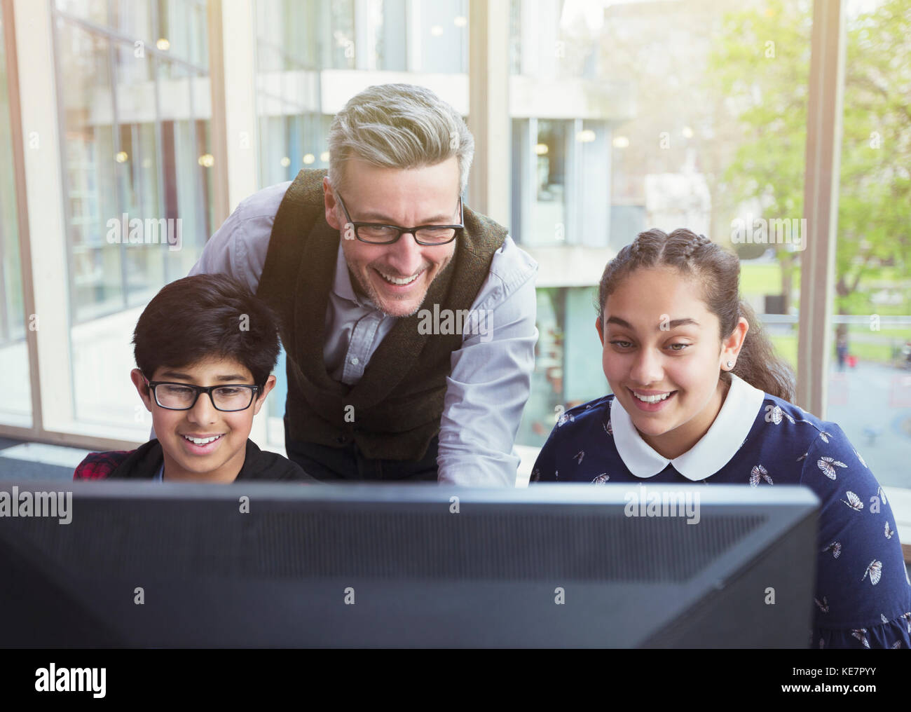 Male teacher and students researching at computer in library Stock ...