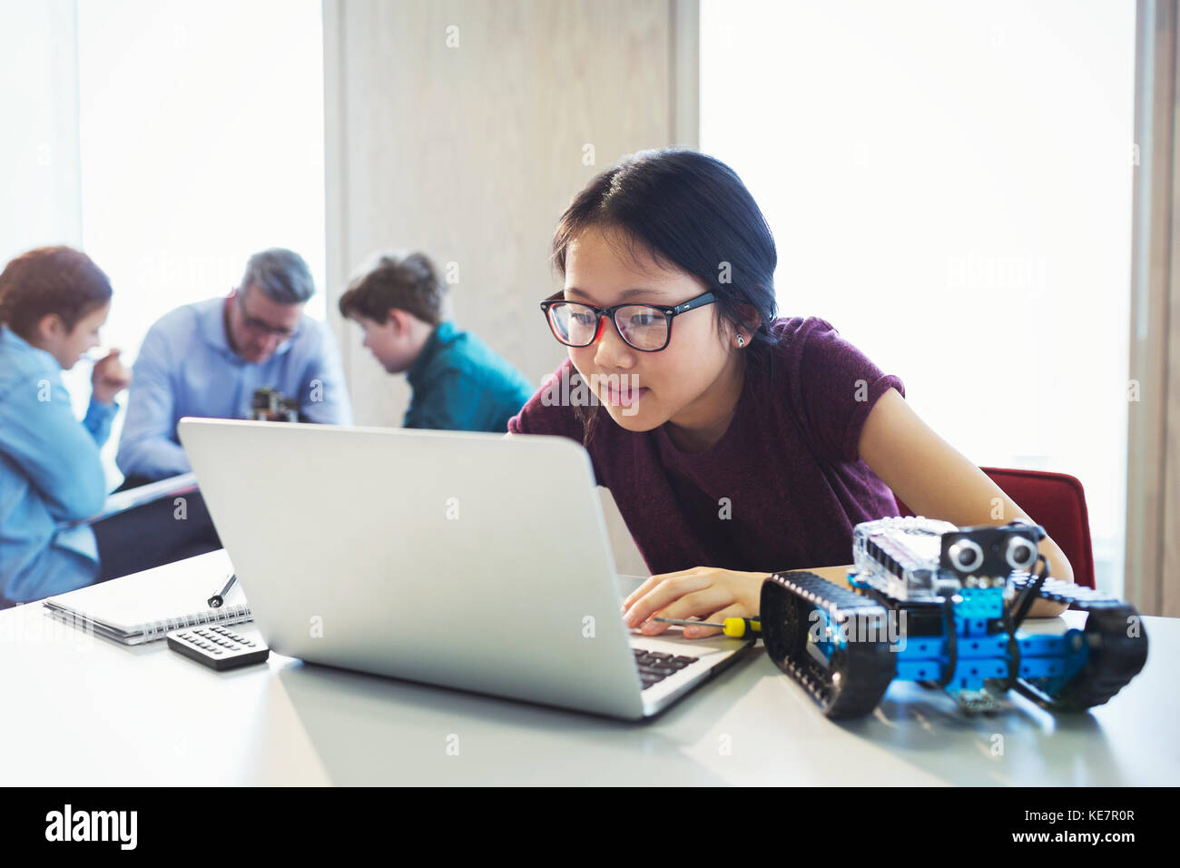 Focused girl student programming robotics at laptop in classroom Stock Photo