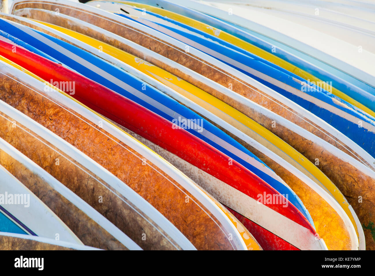 A stack of colourful longboard surfboards placed on the beach,; Waikiki