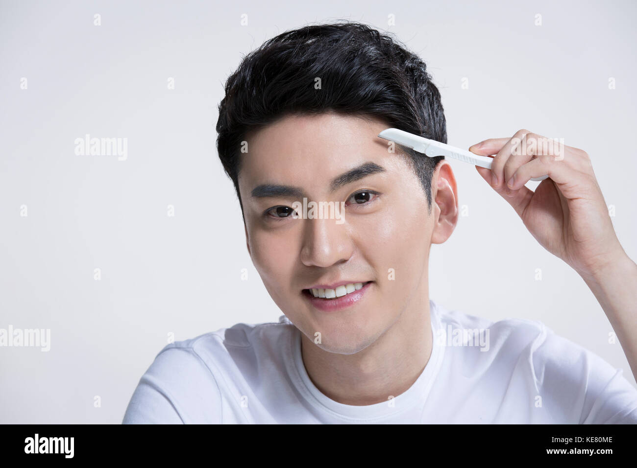 Portrait of young smiling grooming using eyebrow razor Stock Photo Alamy
