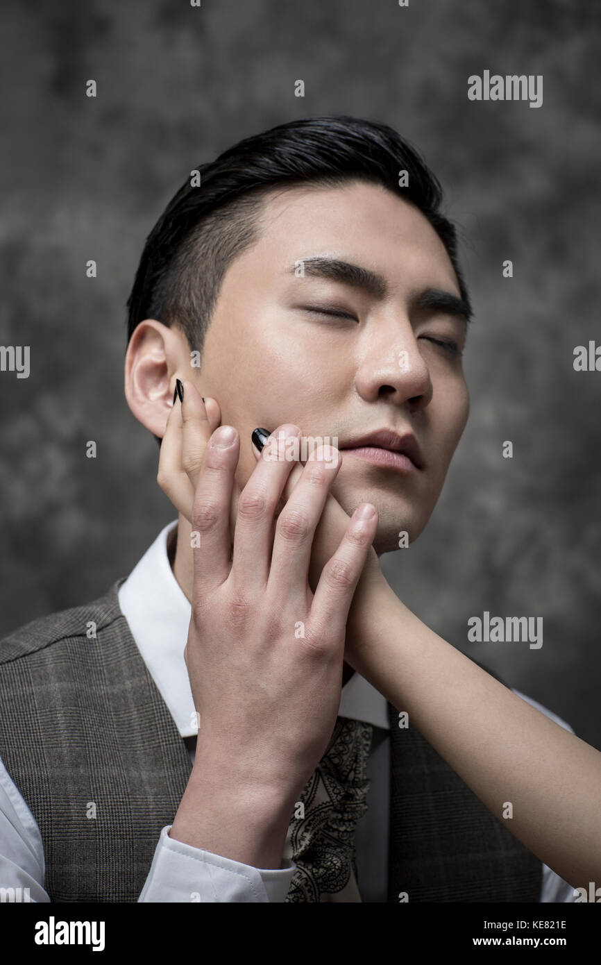 Portrait of young handsome man in retro style suit holding a woman's hand closing his eyes Stock Photo
