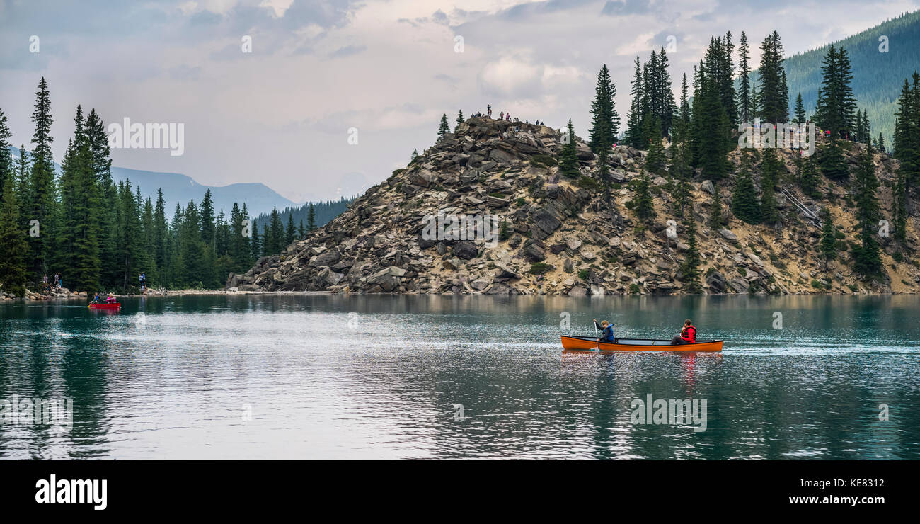 A red canoe in Moraine Lake with a cliff of the Canadian Rocky