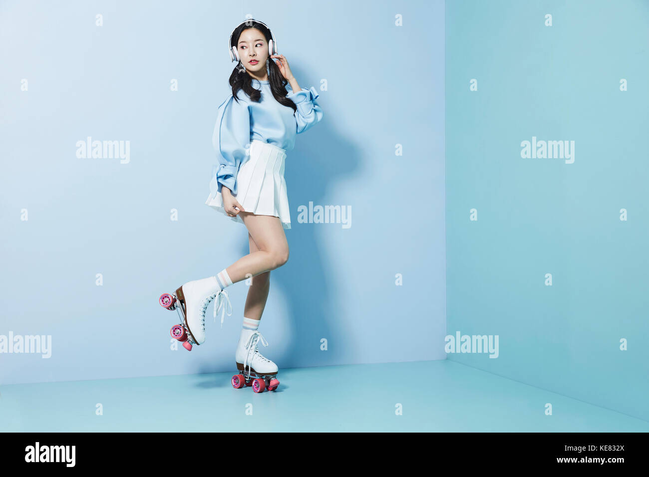 Young woman wearing roller skates and headphones posing on one foot Stock Photo