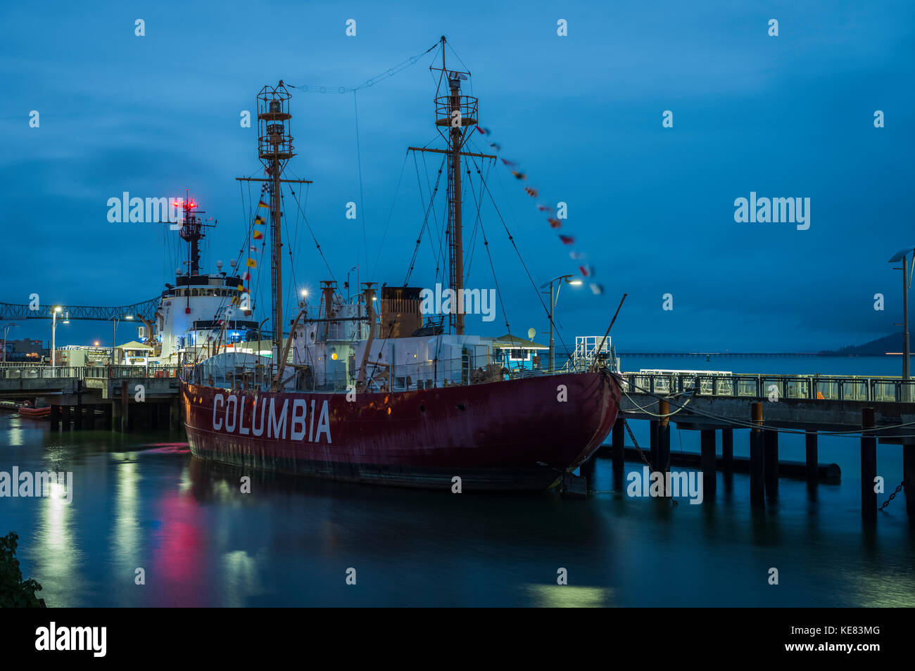 Columbia Lightship docked along the riverfront with lights illuminating the waterfront at dusk