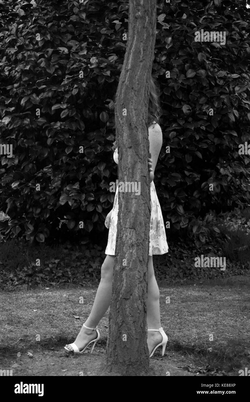 woman hiding behind a tree Stock Photo
