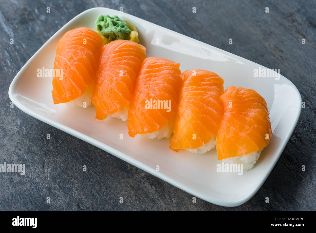 Fresh Japanese Salmon Sushi in white dish with Wasabi and gingers on wood table with copy space Stock Photo