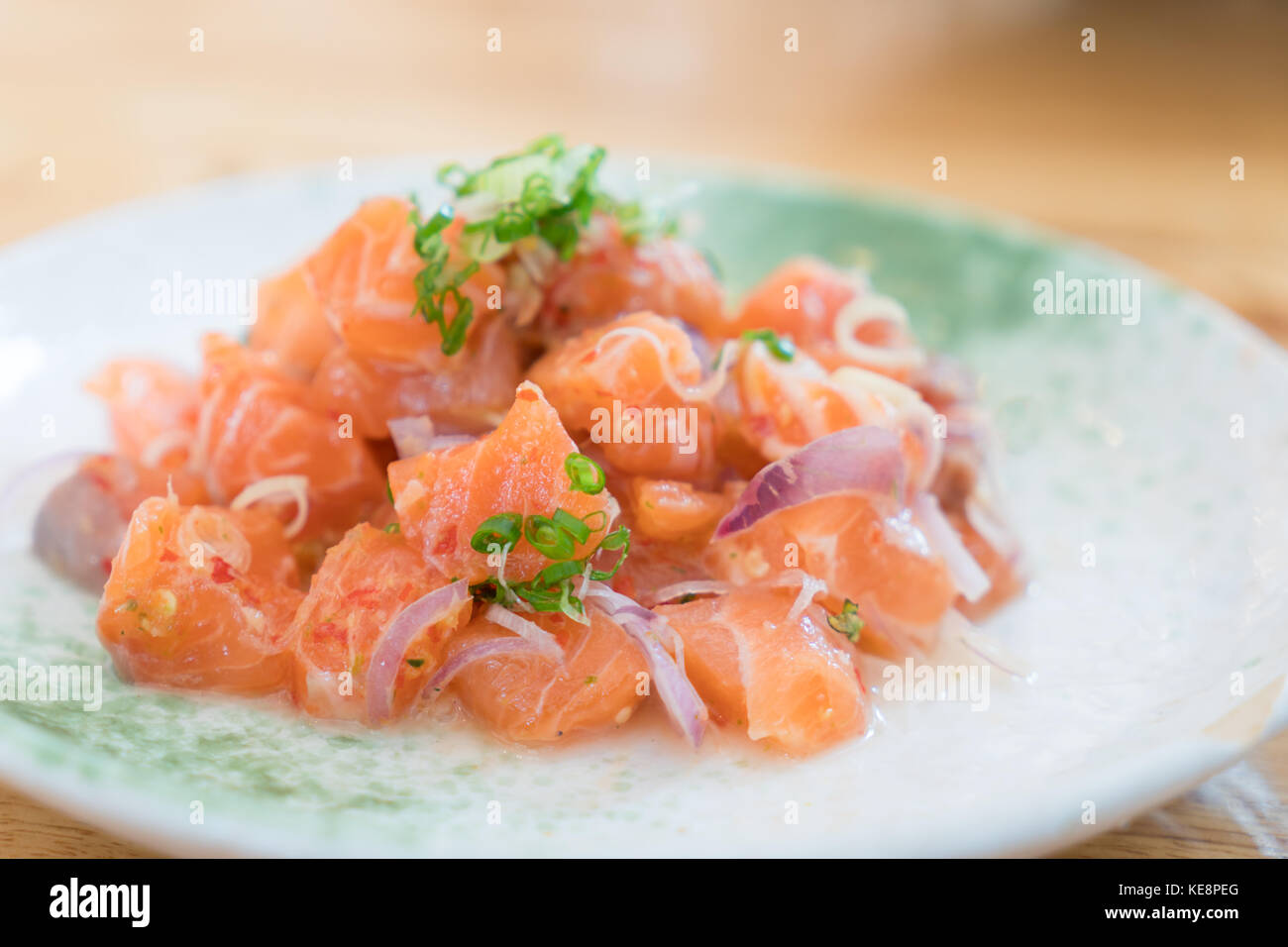 Japan salmon spicy salad with herbs. Mix Japanese and Thai food between Japan salmon sashimi and Thai herb in Japanese restaurant. Stock Photo