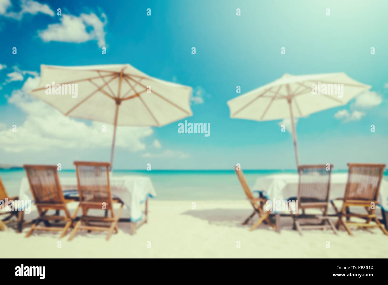 blurred table set and umbrella on the beach in vintage tone for