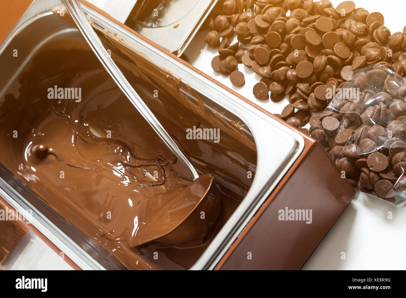 A close-up of a large mettalic container with liquid hot chocolate, next to  it are small pieces of solid Belgian chocolate Stock Photo - Alamy