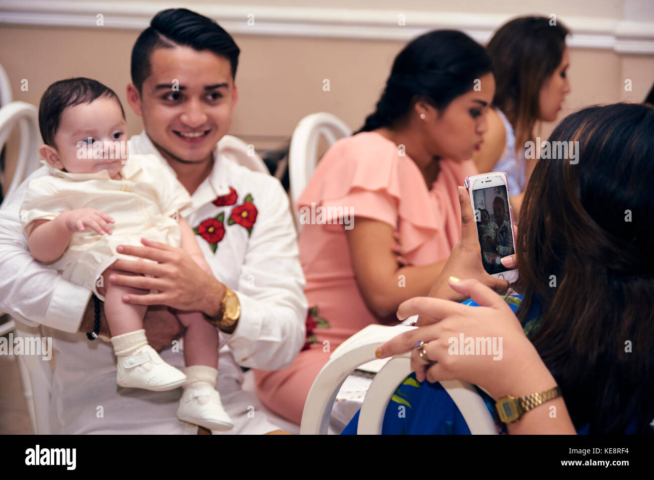 Godfather having his picture taken with the just christened baby at his baptismal party Stock Photo