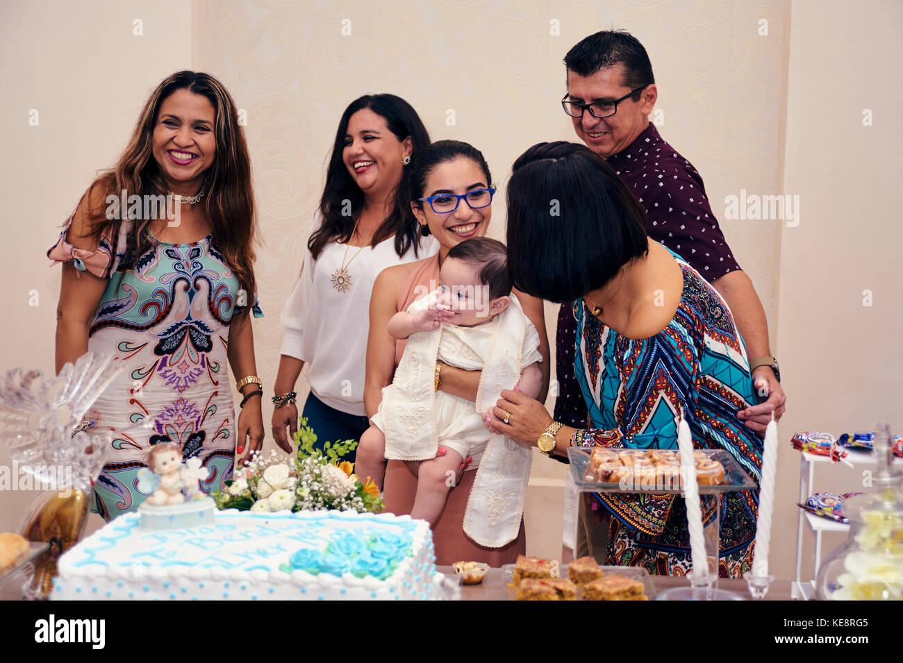 Guests having their picture taken with the just christened baby at his baptismal party Stock Photo