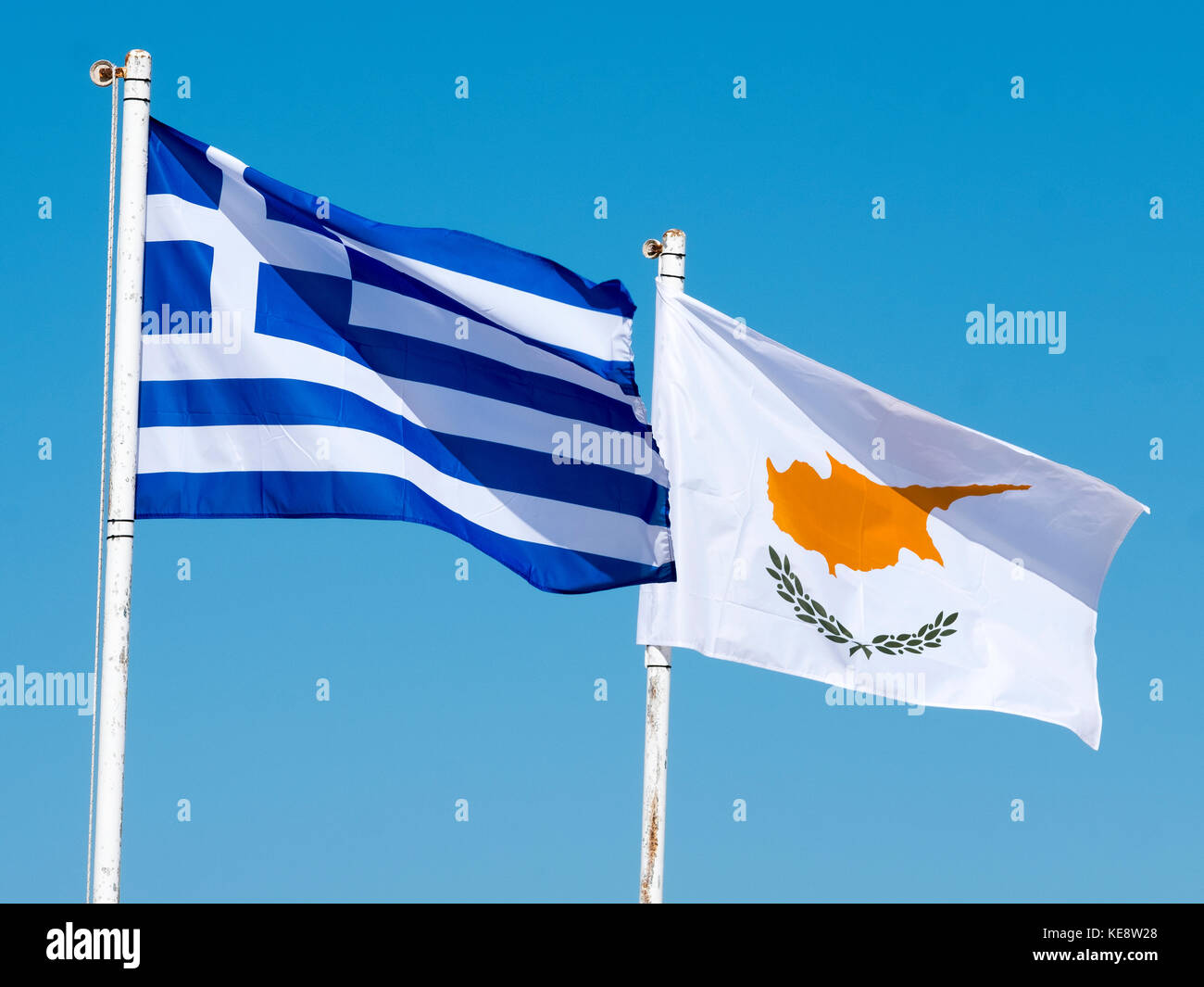 The flags of Greece and Cyprus flutter against a blue sky in Paphos Cyprus. Stock Photo