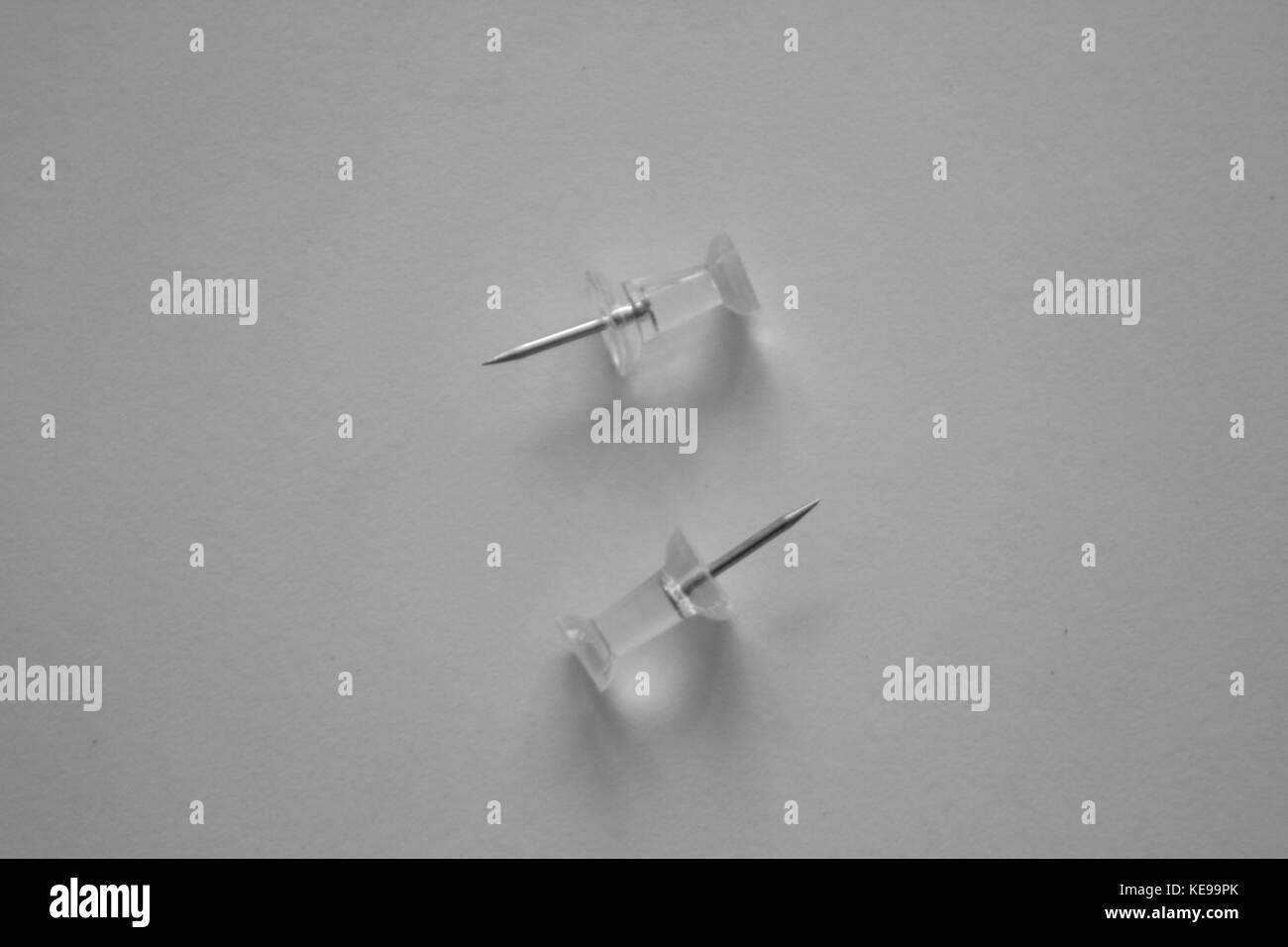 Two clear pushpins facing opposite directions. Stock Photo