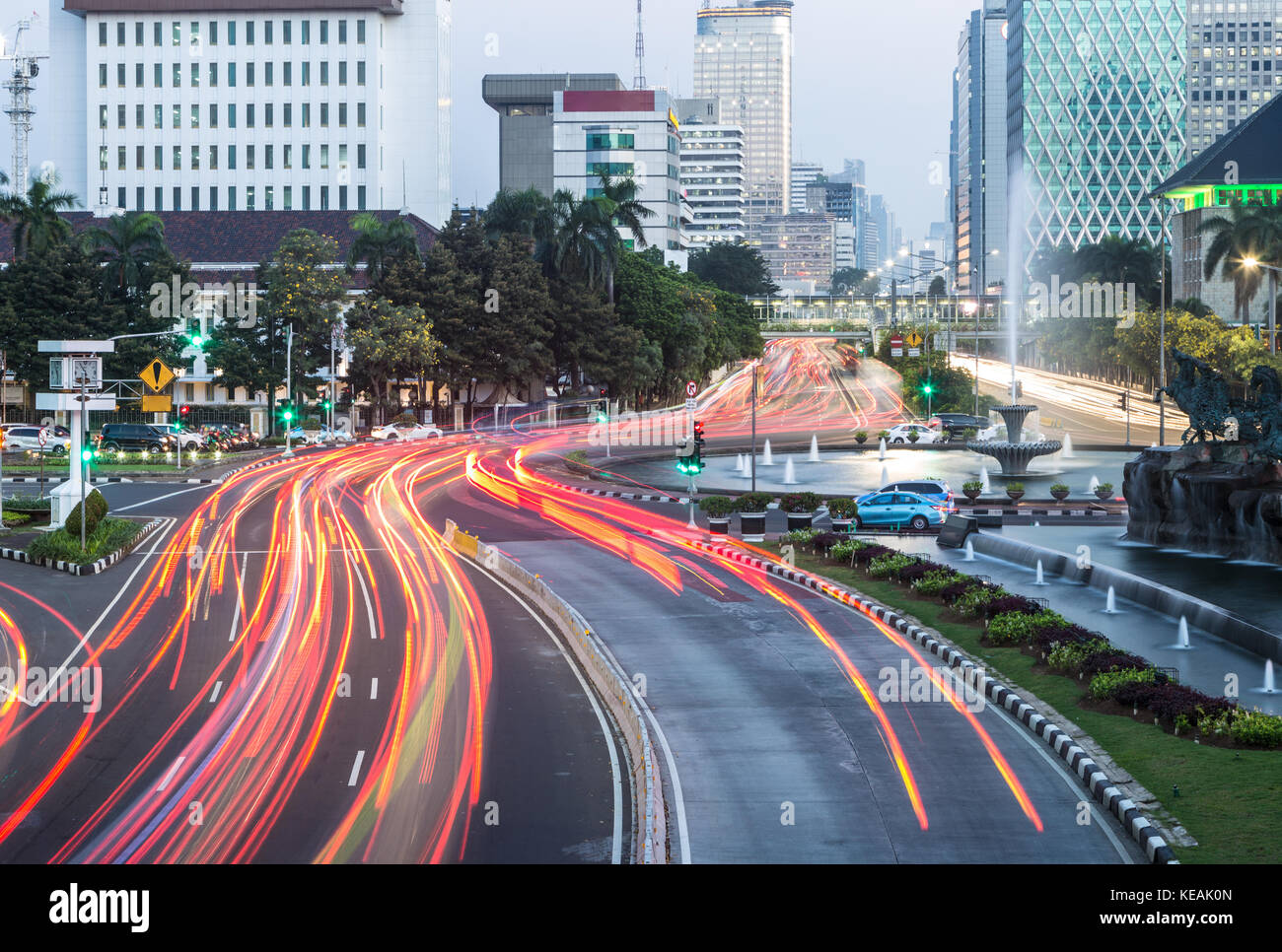 Traffic, captured with blurred motion, rushes along the Thamrin avenue in the heart of Jakarta downtown district in Indonesia capital city at night. Stock Photo
