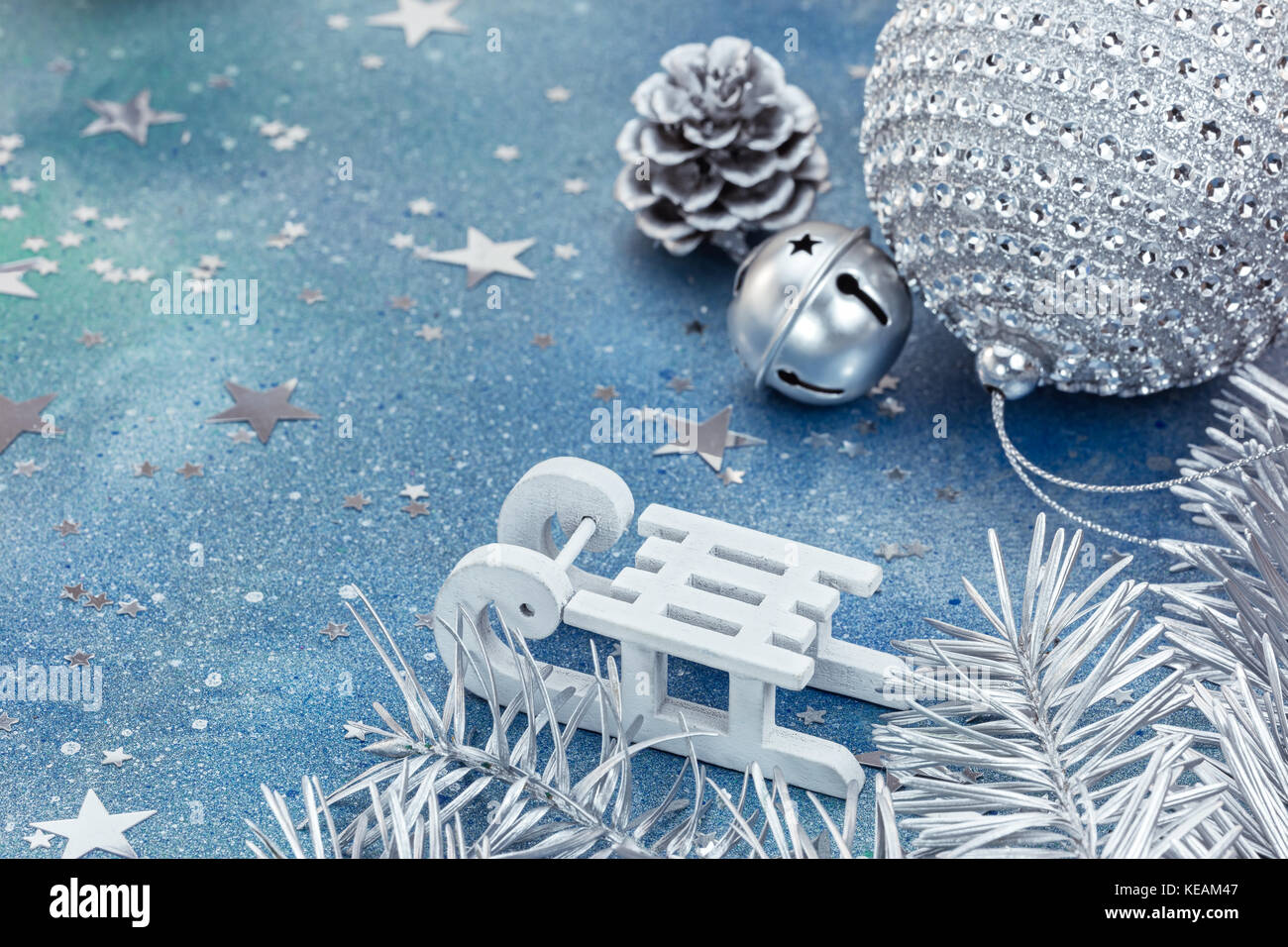 silver christmas decorations with white sledge on blue glittering  background covered with star shaped confetti Stock Photo - Alamy