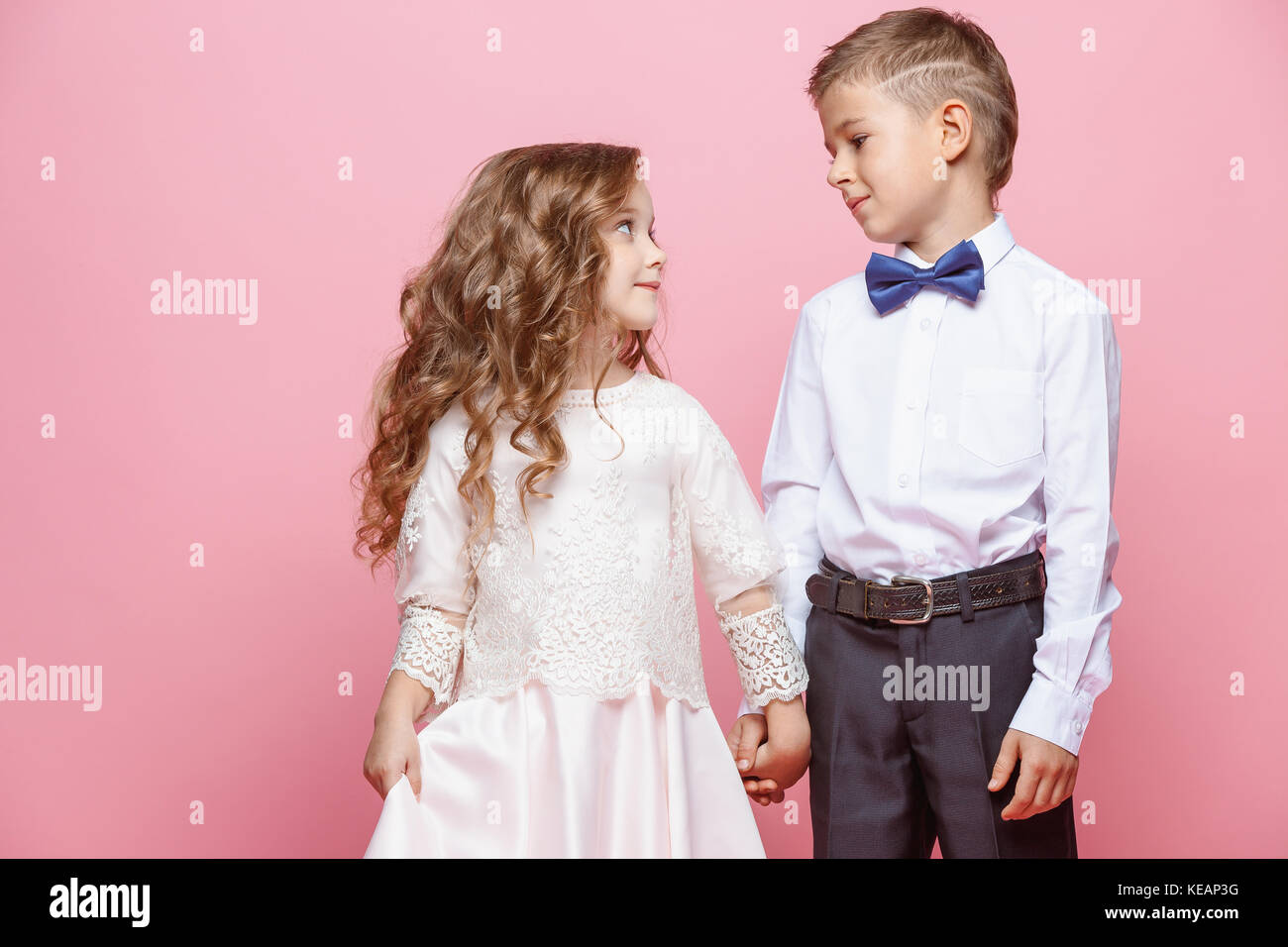 Boy and girl standing in studio on pink background Stock Photo - Alamy