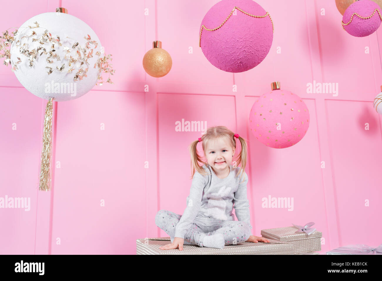 cute little girl sitting in a chair and opens a box with a present for ...