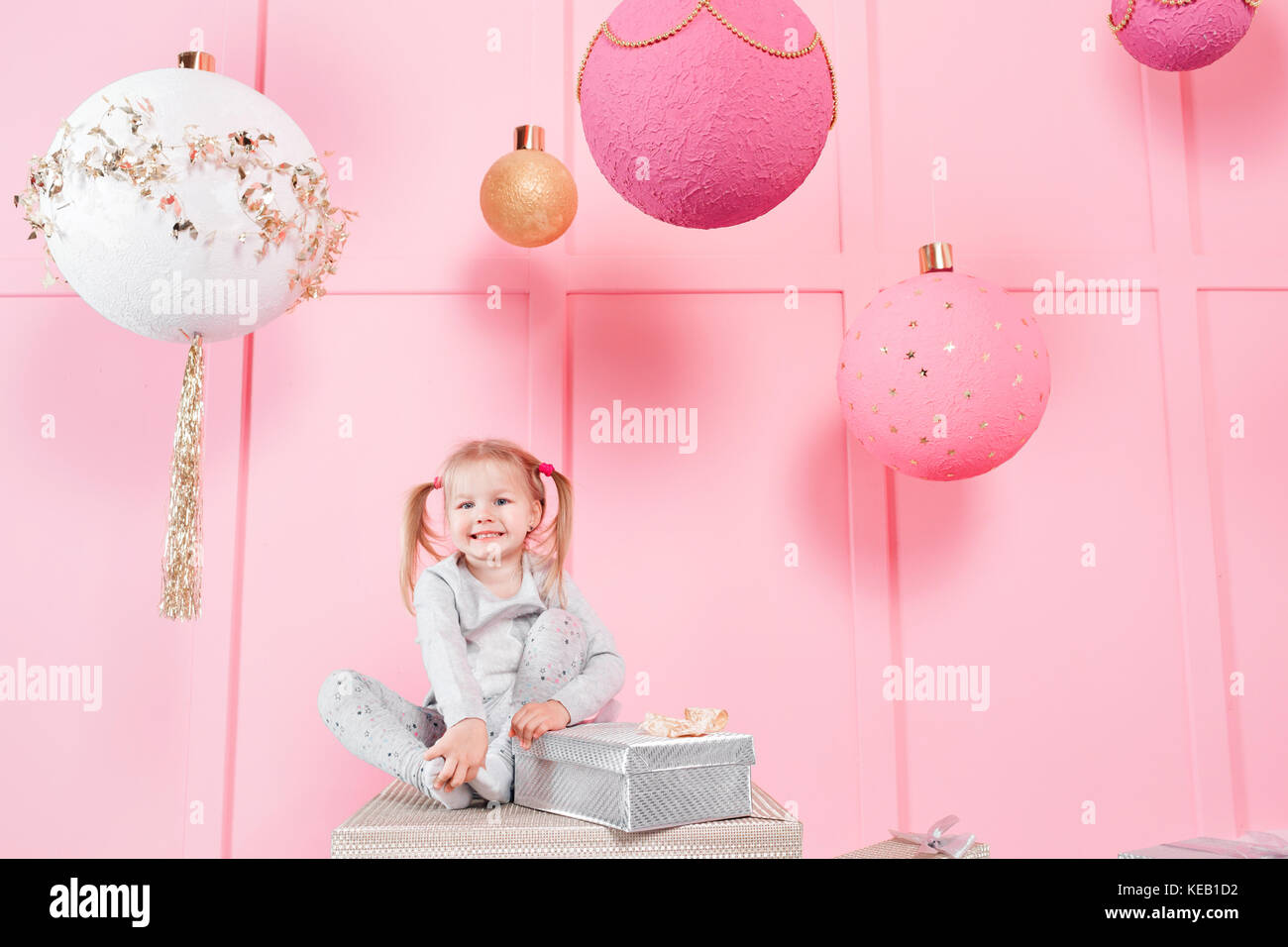 cute little girl sitting in a chair and opens a box with a present for ...