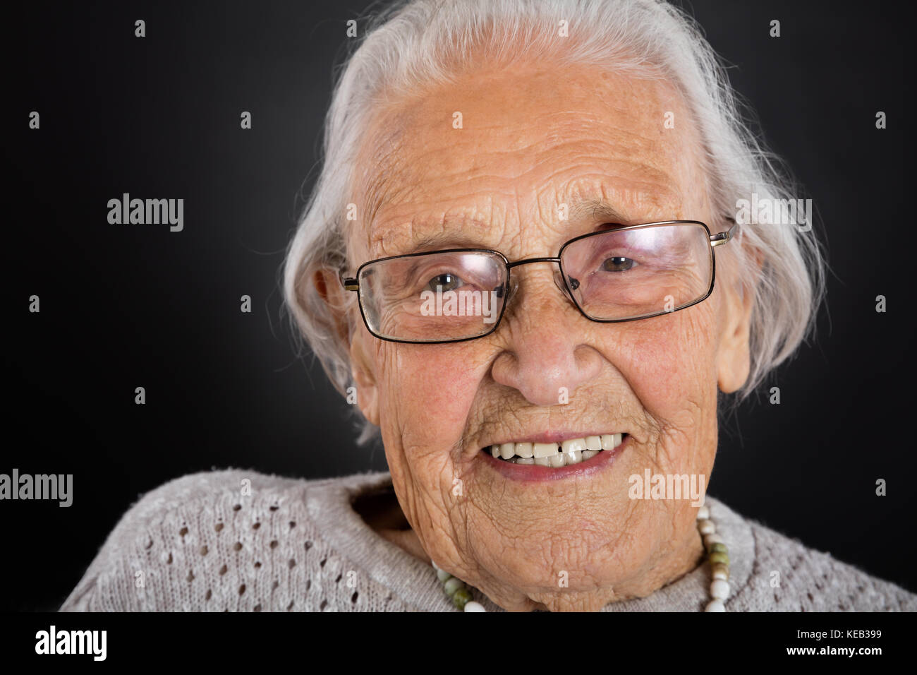 Portrait Of Smiling Senior Woman With Eyeglasses Over Grey Background