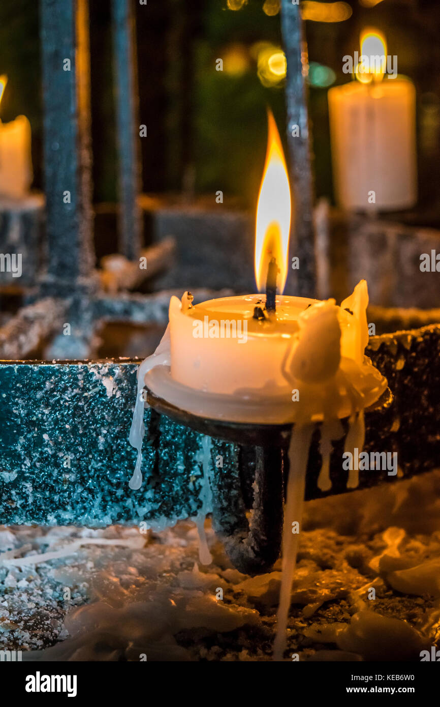 Candles glow in a dark in church. Spirituality, holiday concept. Candlelight in dark, melted wax, old candlestick. Stock Photo