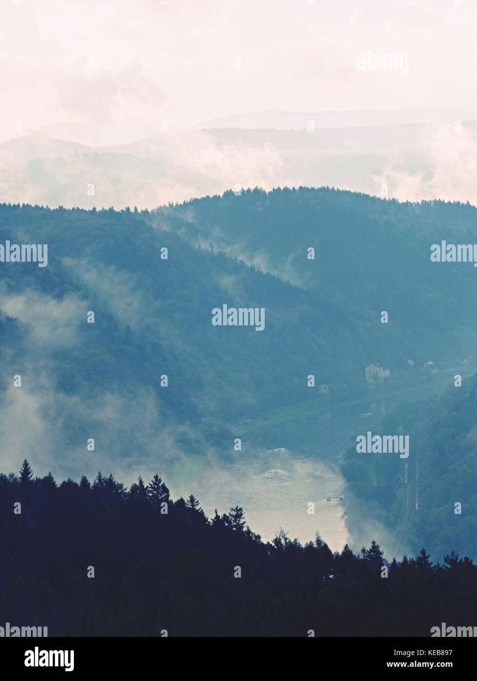 Autumn sunrise in a beautiful mountain within inversion. Peaks of hills strip out from foggy background. Stock Photo