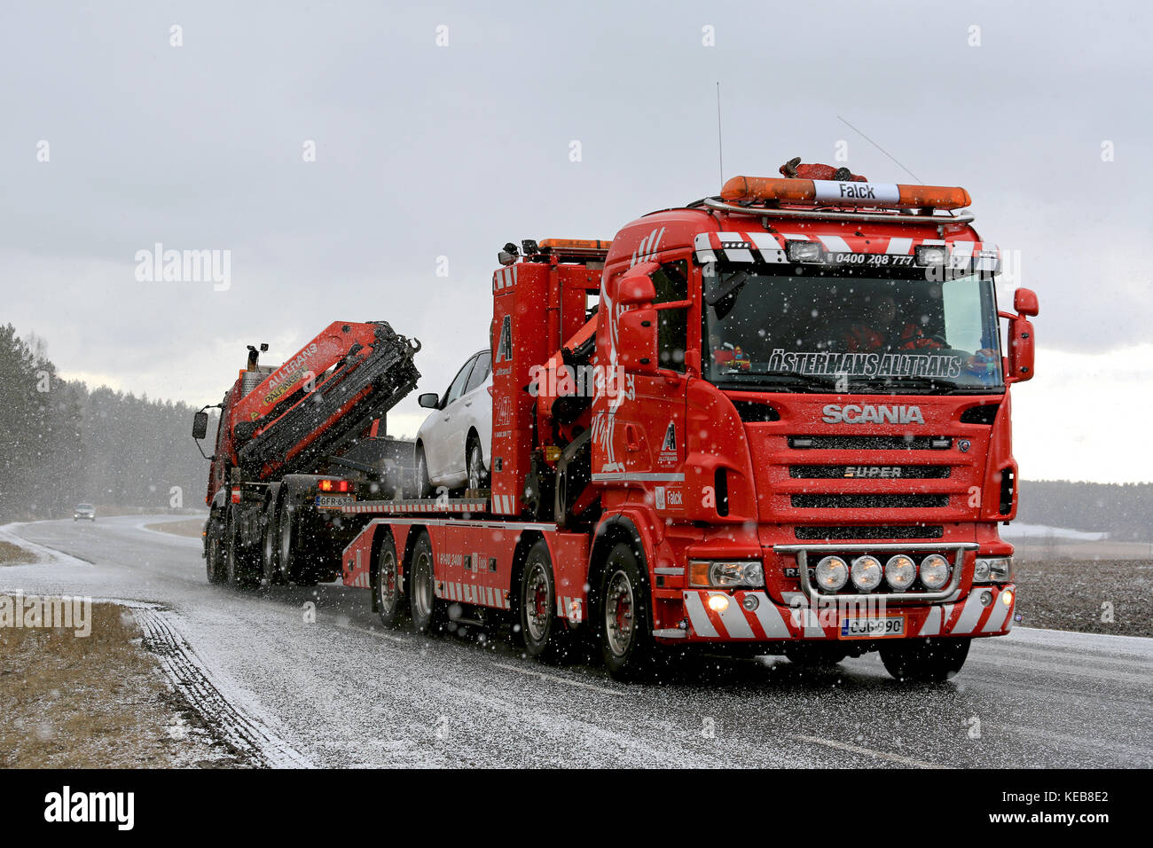 SALO, FINLAND - MARCH 20, 2016: Truck and car are being towed by a heavy duty tow truck in snowfall. Heavy duty towing requires special skills and equ Stock Photo