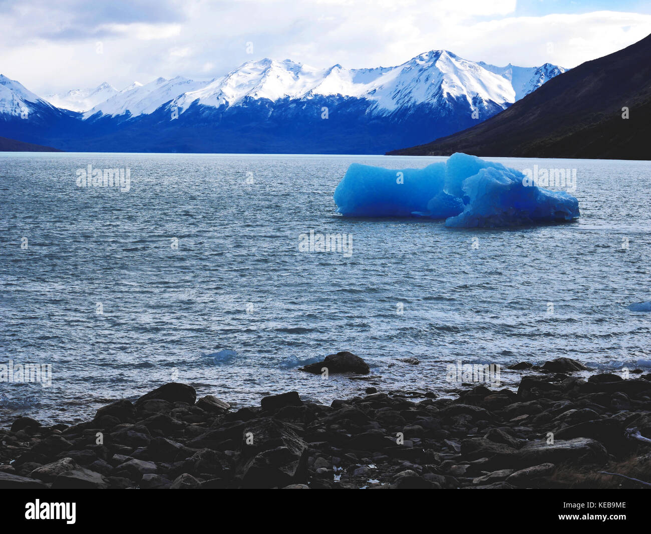 Blue icebergs floating in Lago Argentino with mountain backdrop, Patagonia, Argentina Stock Photo