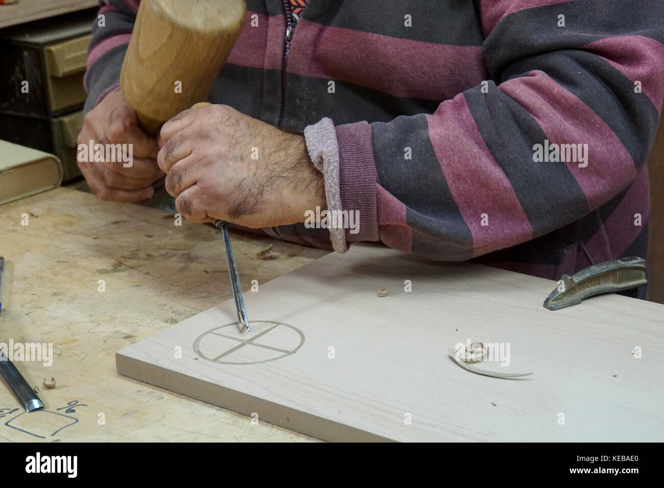 A man engraving a block of wood with a mallet and chisel Stock Photo