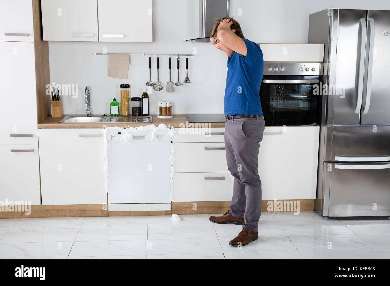 Young Man Shocked On Seeing Foam Coming Out Of Dishwasher At Home Stock