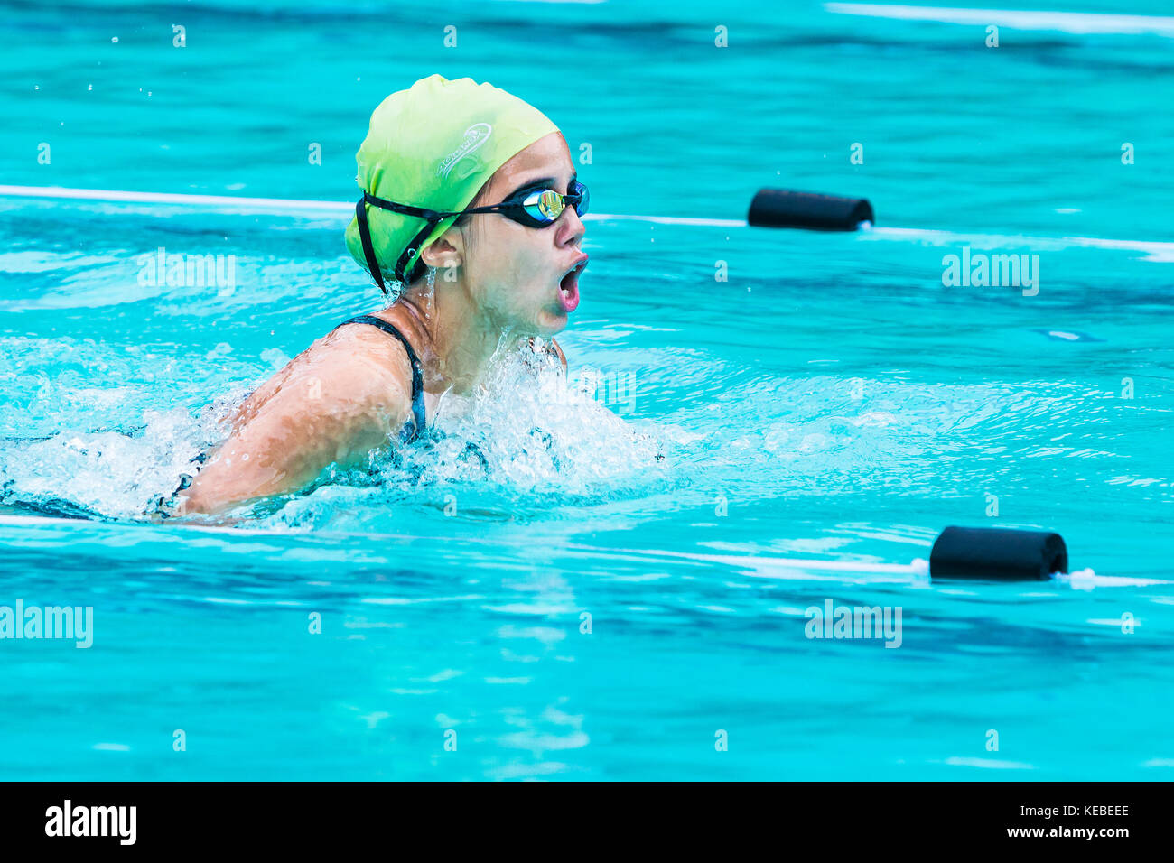 Chiang Mai, Thailand - 11 October 2017 - young female swimmer races in breath stroke and raises up to catch her breath at a school swimming pool in Ch Stock Photo