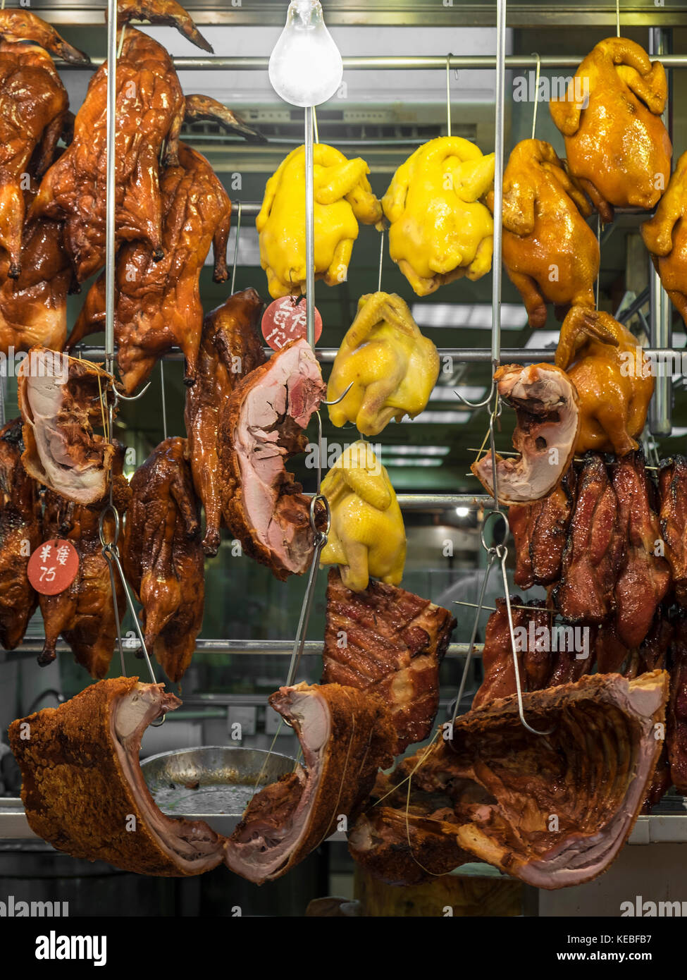 Cooked cuts of meat hanging in a market at night in Hong Kong Stock