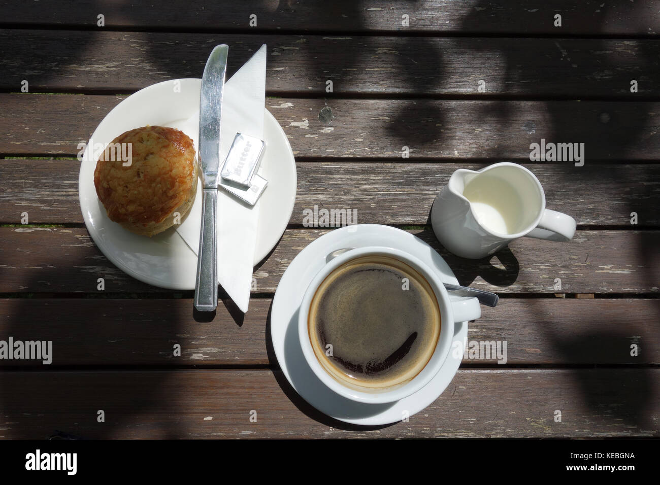 Coffee and cheese scone on table in sunshine Stock Photo