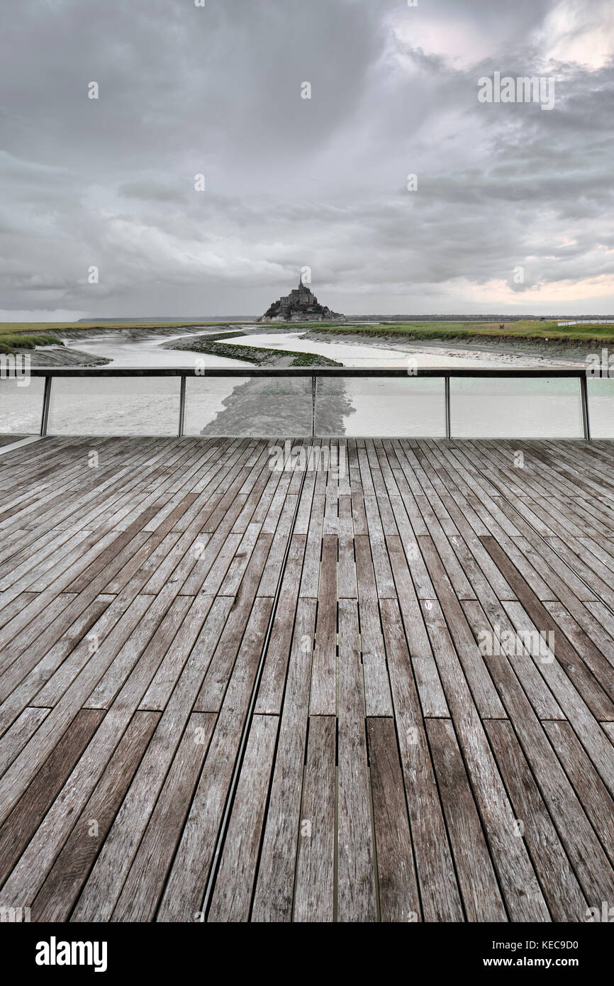 A distant view of Mont Saint Michel and storm clouds from the river Couesnon barrage in Normandy France Stock Photo