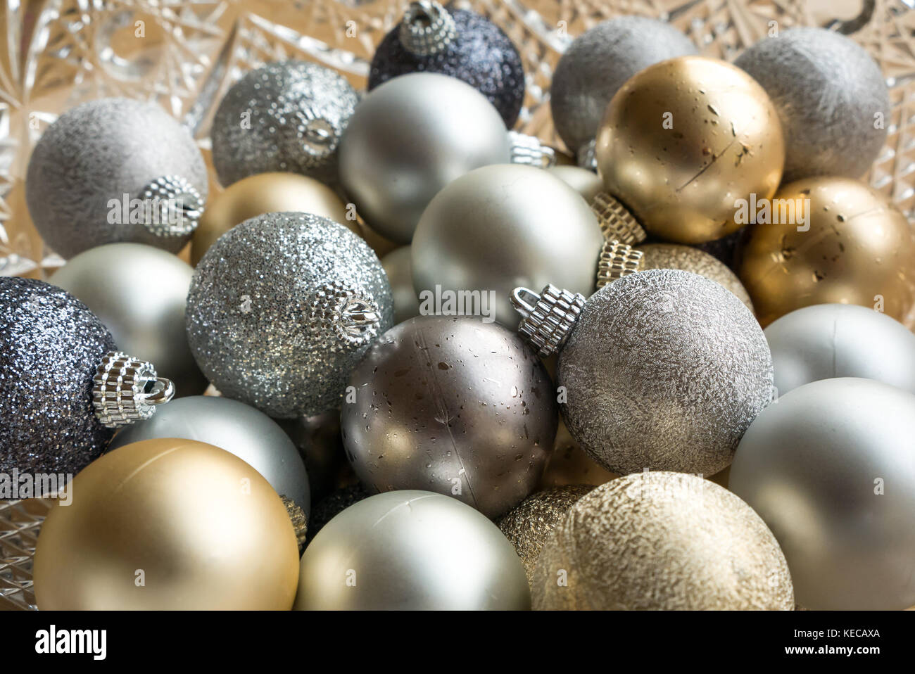 Close up of gold, silver and blue sparkling Christmas  baubles in a crystal bowl Stock Photo