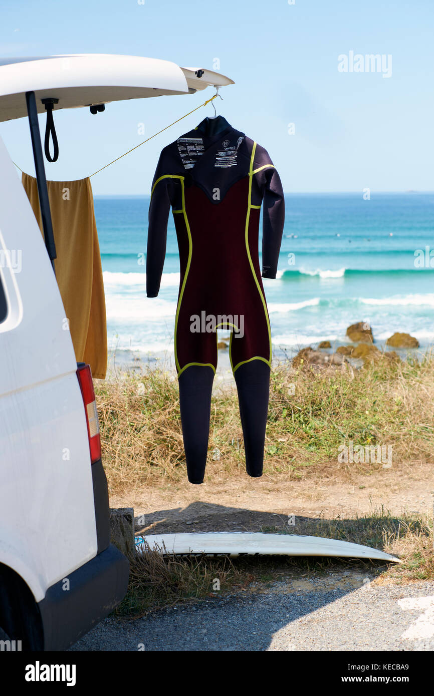 A surfers van parked at the beach with a wetsuit hanging outside to dry. Stock Photo