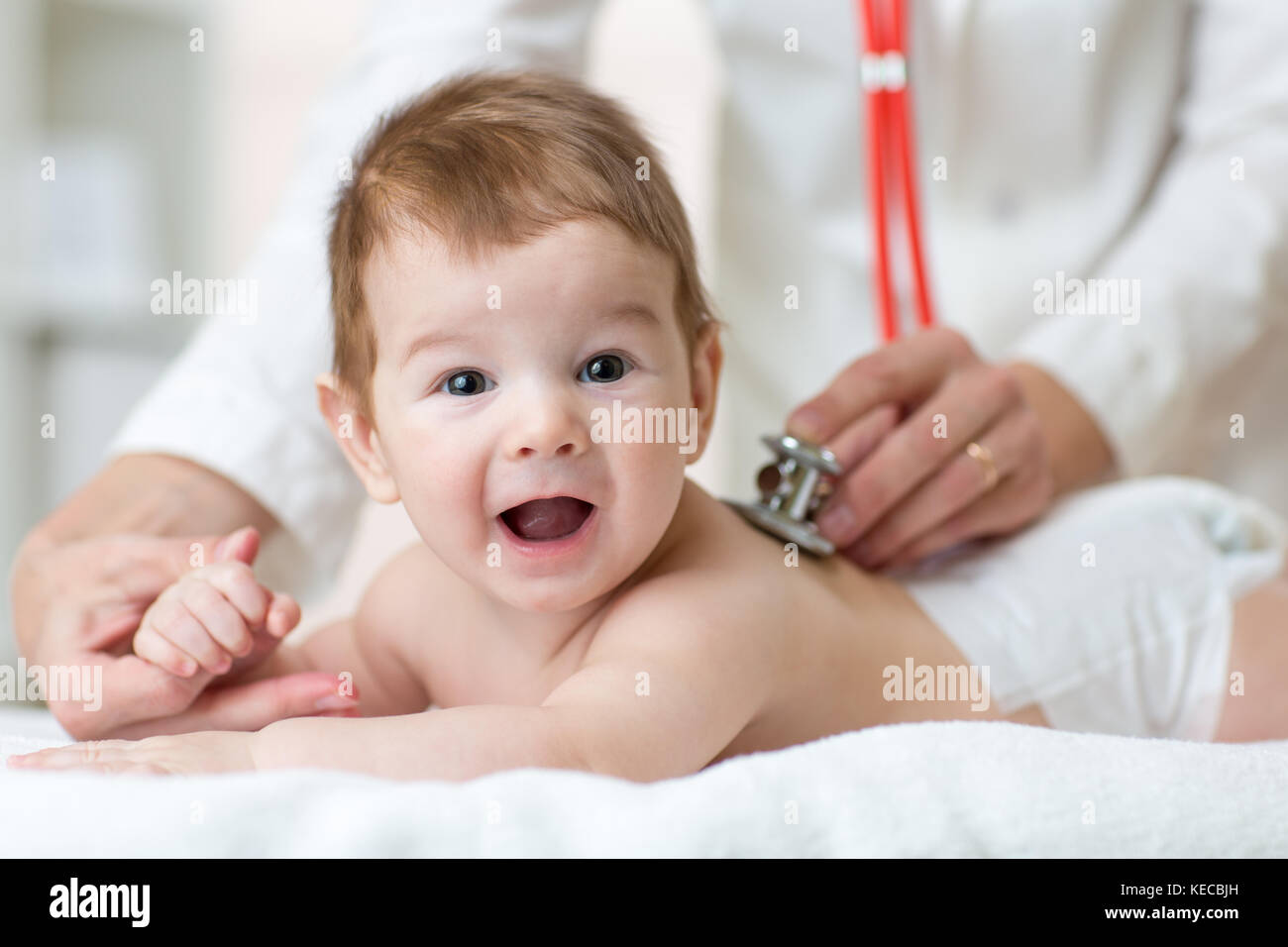 Pediatrician female doctor examines baby boy with stethoscope checking heart beat Stock Photo