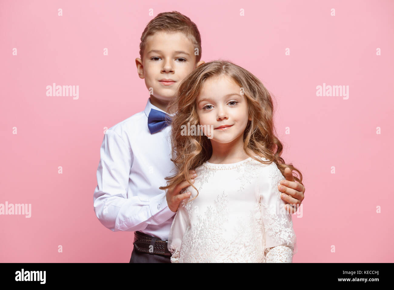 Boy and girl standing in studio on pink background Stock Photo - Alamy