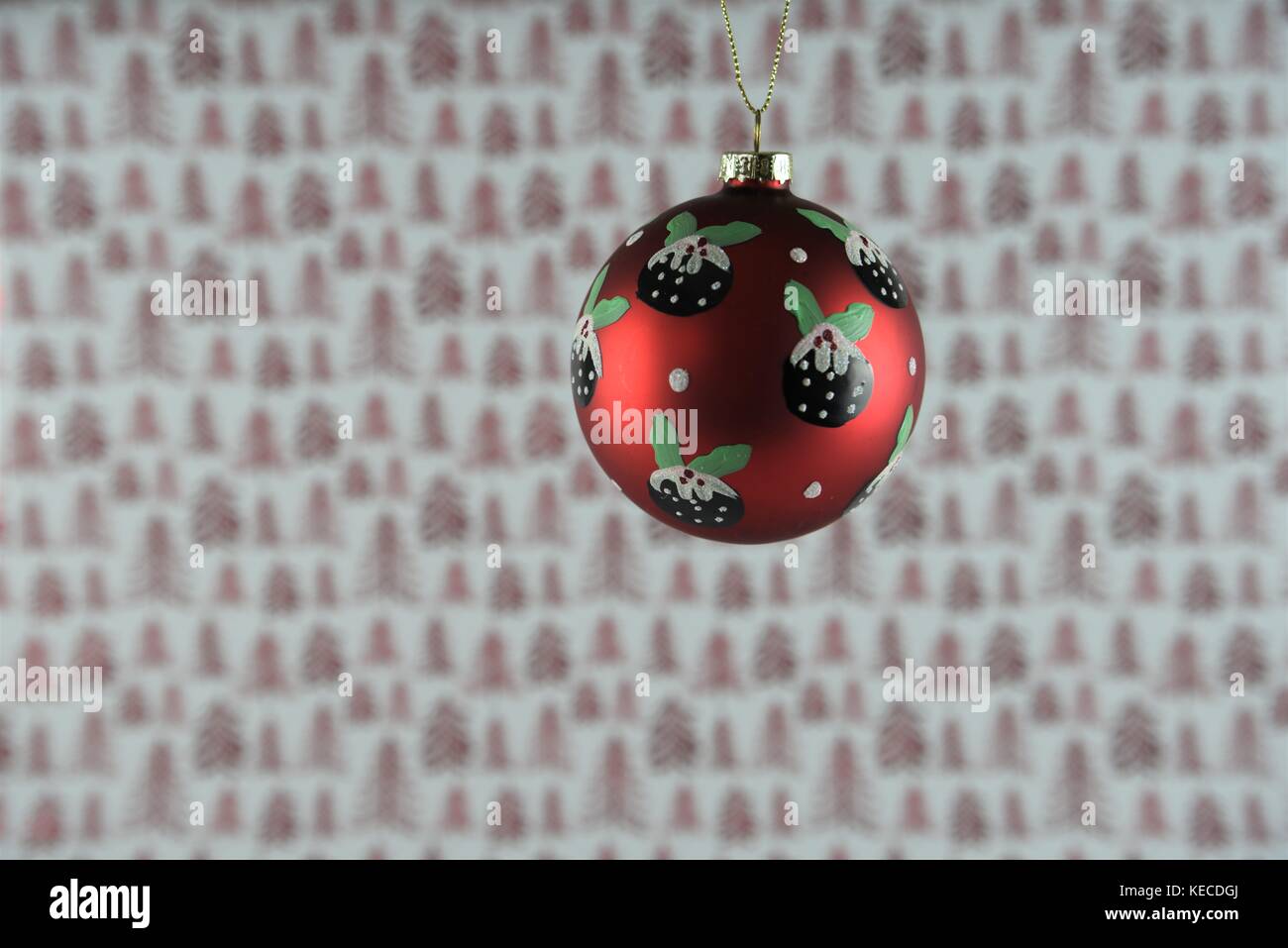 red white Christmas photography picture of hanging up Christmas decoration of xmas pudding pattern bauble with xmas wrapping paper background Stock Photo