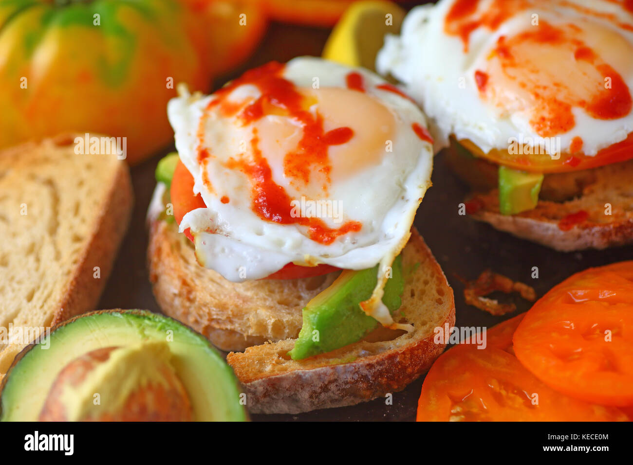Fried eggs topped with hot chili sauce on avocado toast Stock Photo