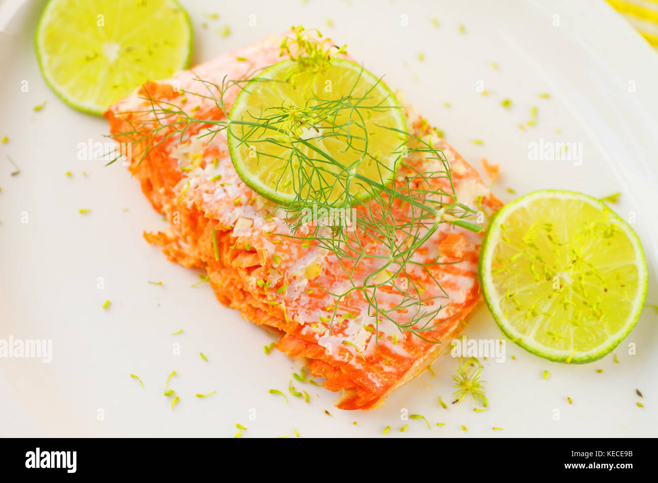 Portion of roasted salmon with lime slices and fresh dill on a white platter with room for text Stock Photo