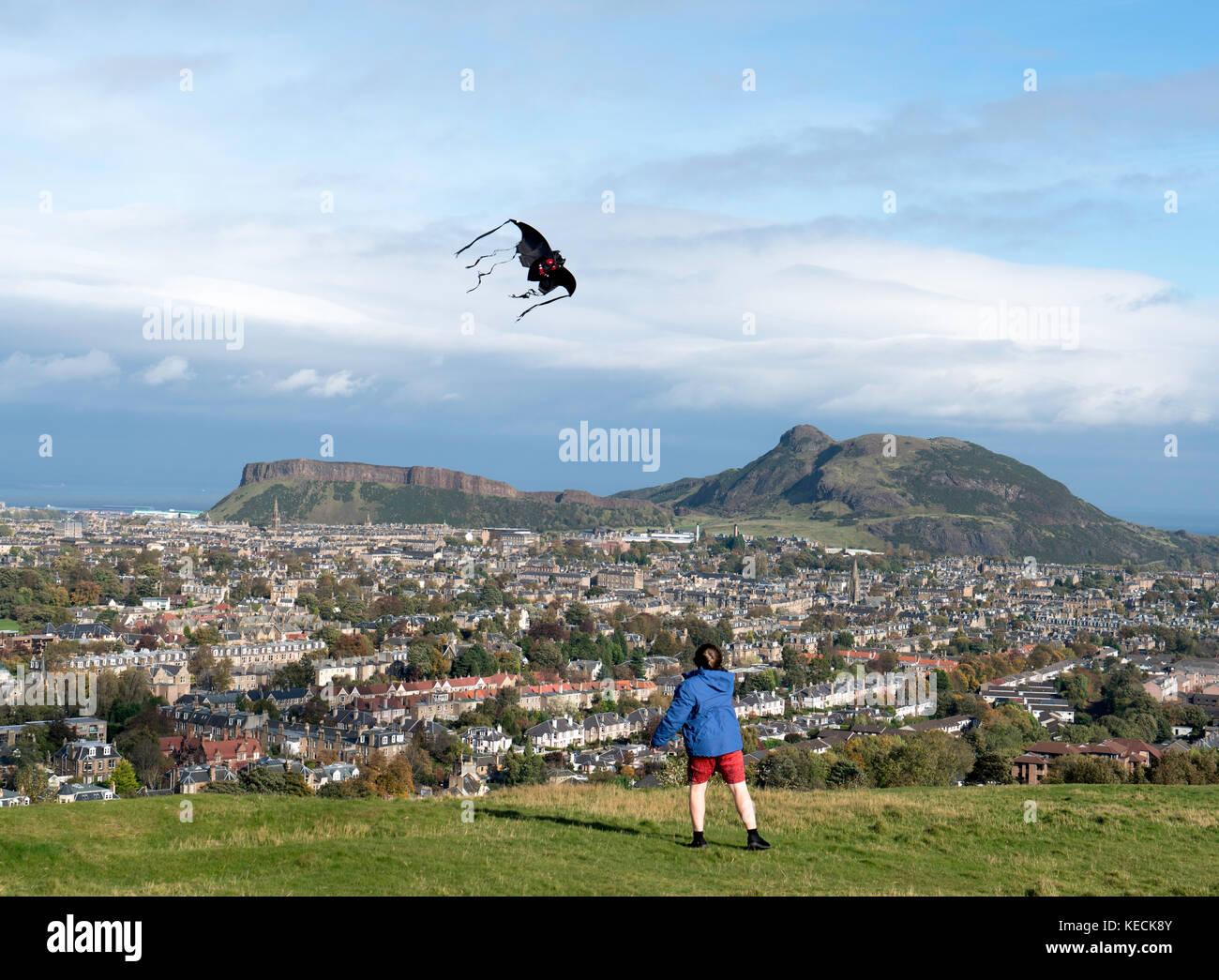 View of boy flying kite and Salisbury Crags and Arthur's Seat hill overlooking Edinburgh, Scotland, United Kingdom Stock Photo