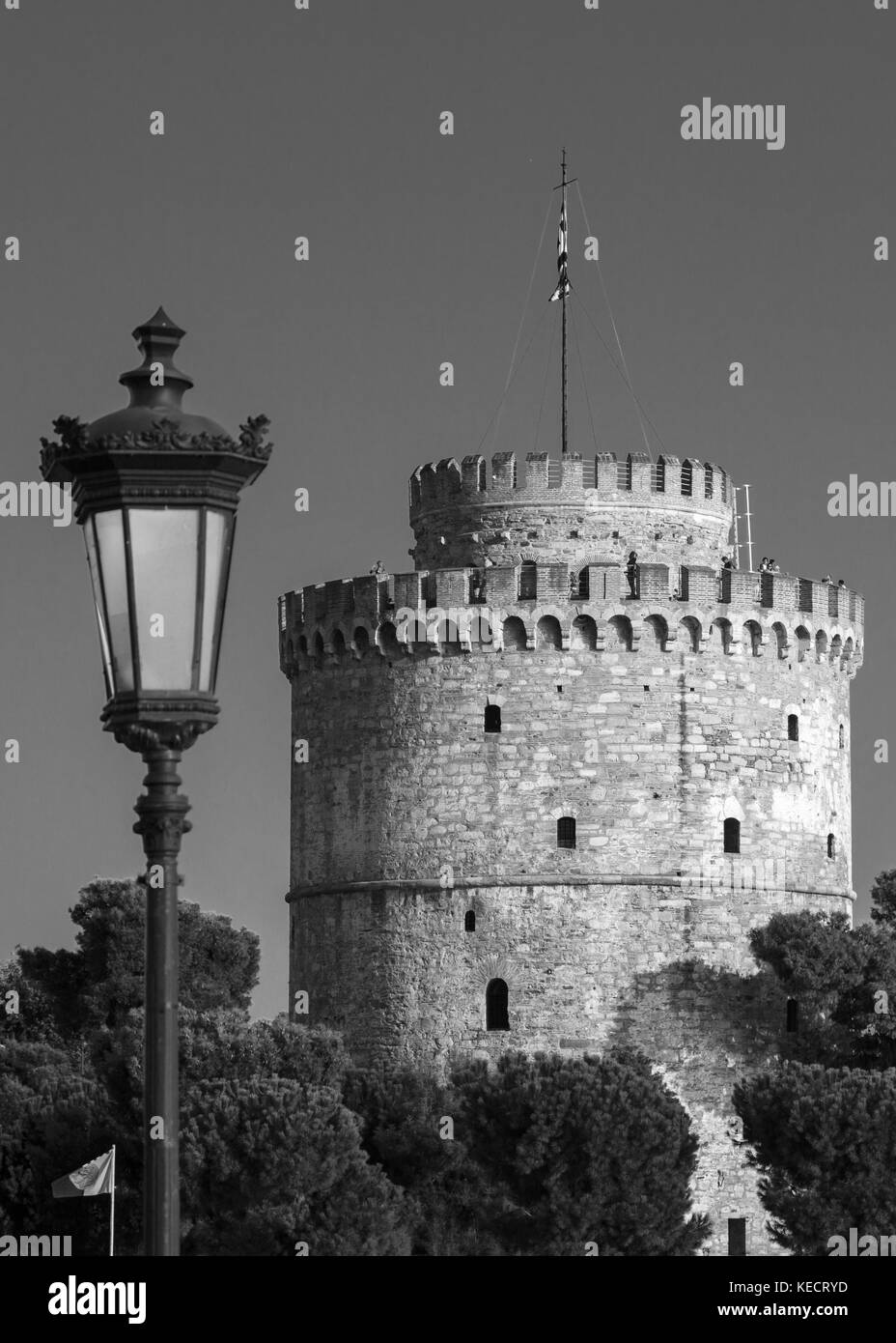 b&w one urban metal lantern with one lamp just against a clear sky and the main city attractions of the white tower, Greece, Thessaloniki Stock Photo