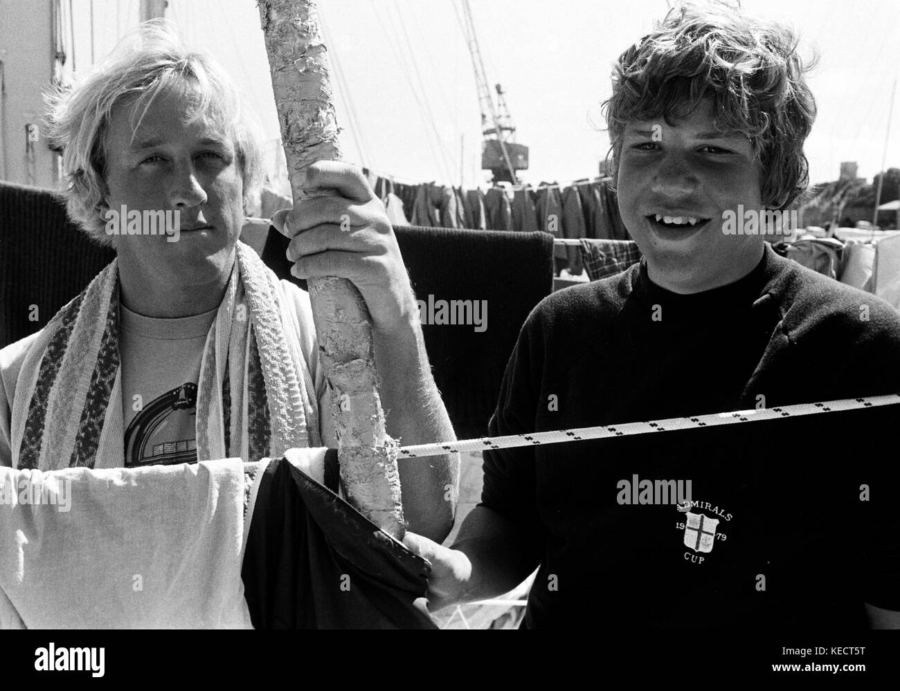 AJAXNETPHOTO. 17TH AUGUST, 1979. PLYMOUTH, ENGLAND. - YACHT CREW - (L-R) COURTENY JENKINS FROM OWINGS MILLS, MD. AND TEDDY TURNER IV OF ATLANTA, SON OF YACHT OWNER AND SKIPPER TED TURNER, RELAX ON BOARD THE YACHT AT MILLBAY AFTER FINISHING THE STORMY 605 MILE FASTNET RACE. PHOTO:JONATHAN EASTLAND/AJAX REF:791708 1 Stock Photo