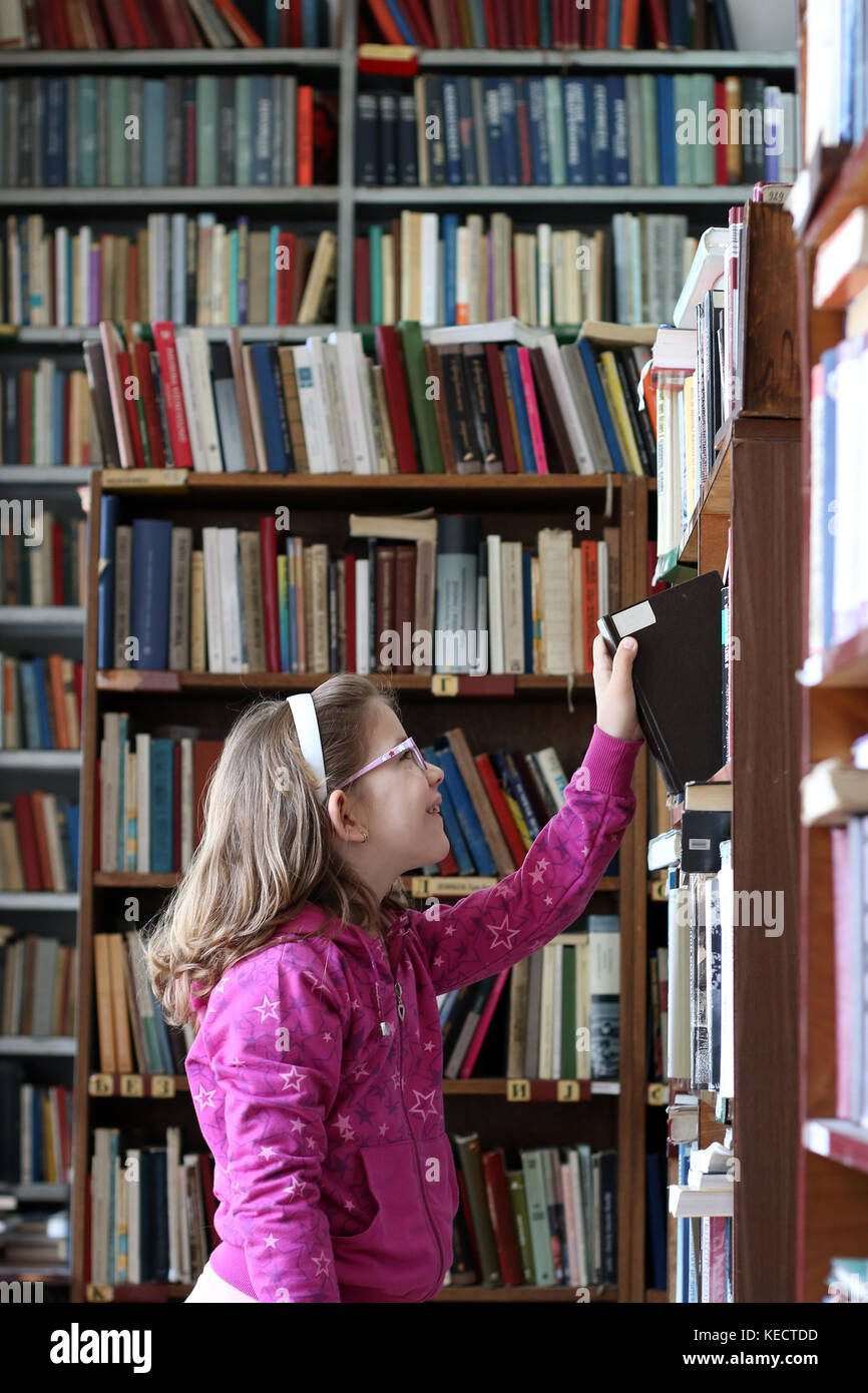 little girl taking a book in the library Stock Photo - Alamy