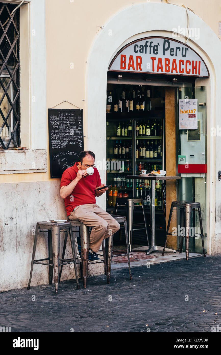 A man sips a cappuccino in front of a classic neighborhood coffee bar in the historic center of Rome, Italy Stock Photo
