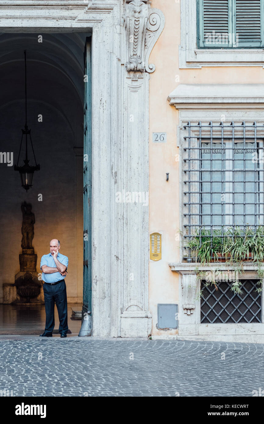 A doorman stands in the doorway of a palazzo in Rome, Italy's Piazza di Pietra Stock Photo